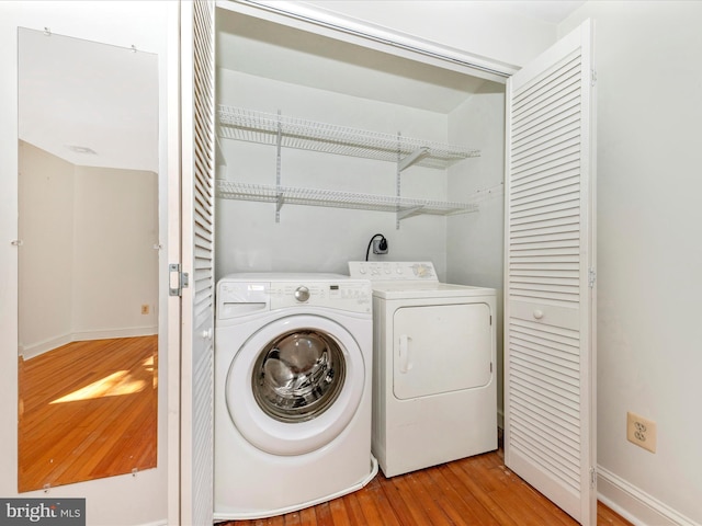 washroom featuring laundry area, light wood-type flooring, washing machine and clothes dryer, and baseboards