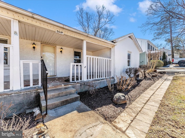 property entrance featuring a porch and stucco siding