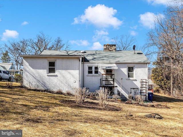 back of house featuring a chimney and stucco siding