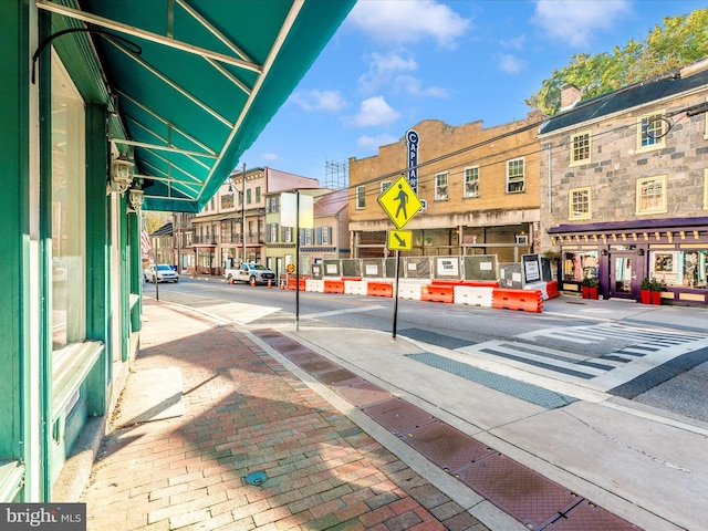 view of road with traffic signs, curbs, sidewalks, and street lights