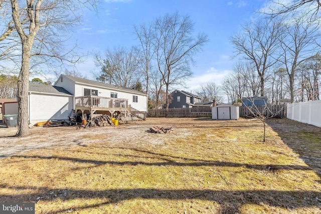 view of yard with a storage shed, a fire pit, a fenced backyard, an outbuilding, and a wooden deck