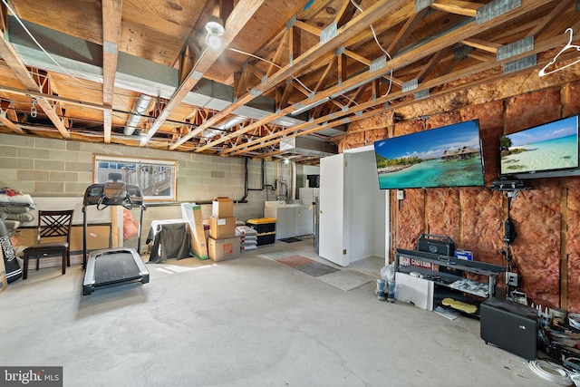 unfinished basement with concrete block wall and washer and clothes dryer