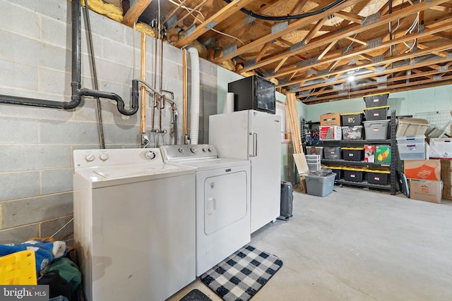 clothes washing area featuring concrete block wall, laundry area, and independent washer and dryer