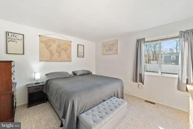 bedroom featuring baseboards, visible vents, and light colored carpet