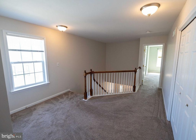 hall featuring carpet floors, an upstairs landing, and baseboards