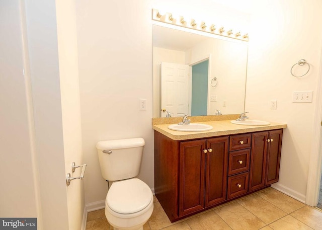 full bathroom with baseboards, a sink, toilet, and double vanity