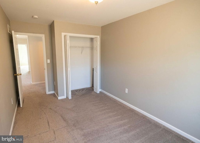 unfurnished bedroom with baseboards, a closet, and carpet flooring