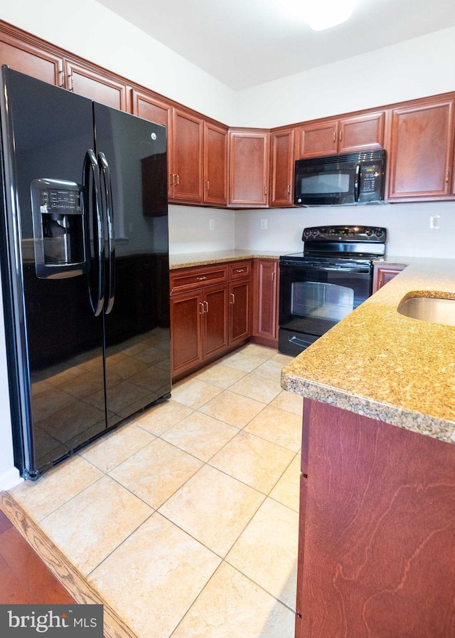 kitchen with light tile patterned floors, black appliances, a sink, and light countertops