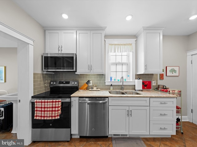 kitchen featuring light countertops, decorative backsplash, stainless steel appliances, white cabinetry, and a sink