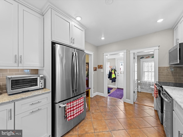 kitchen with decorative backsplash, white cabinets, a toaster, and stainless steel appliances