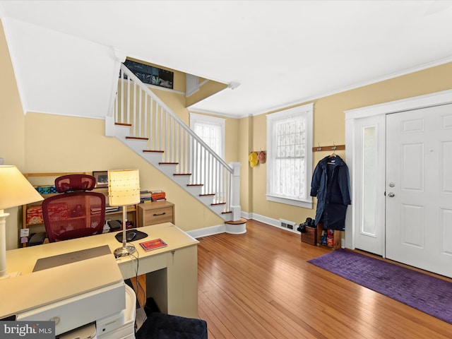 entrance foyer featuring hardwood / wood-style floors, crown molding, stairway, and visible vents