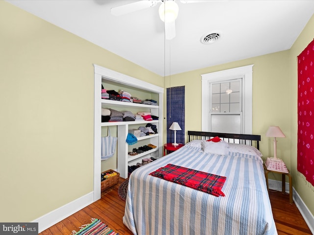 bedroom featuring a ceiling fan, wood finished floors, visible vents, and baseboards