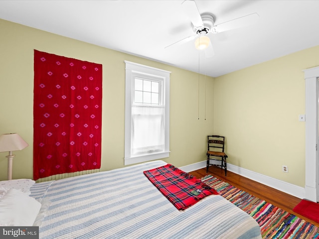 bedroom featuring baseboards, wood finished floors, and a ceiling fan