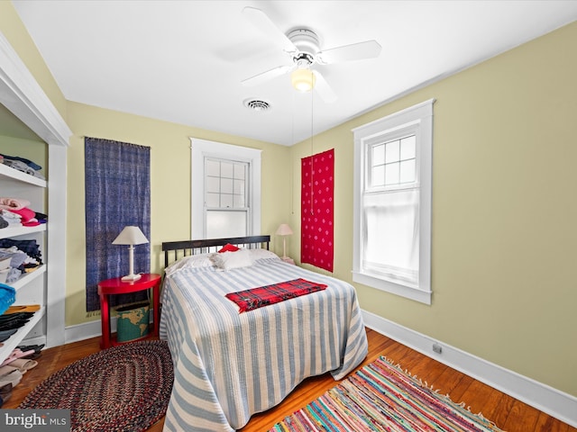 bedroom with visible vents, a ceiling fan, baseboards, and wood finished floors