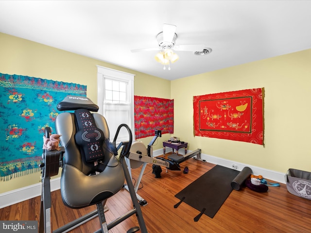 exercise area with ceiling fan, visible vents, baseboards, and wood finished floors