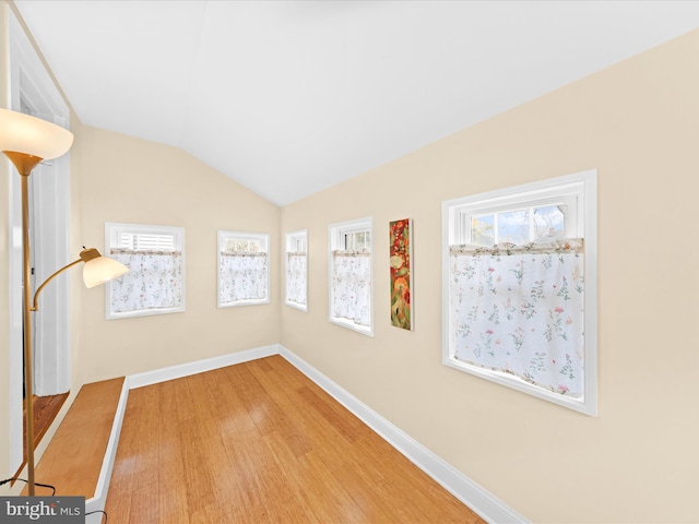 empty room with baseboards, lofted ceiling, and wood finished floors