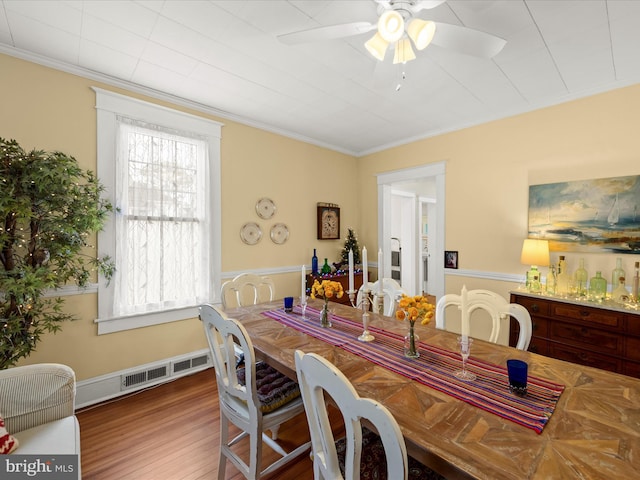 dining area with a ceiling fan, crown molding, wood finished floors, and visible vents