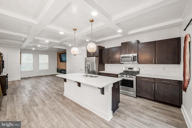 kitchen with stainless steel appliances, light countertops, light wood-style floors, open floor plan, and a kitchen bar