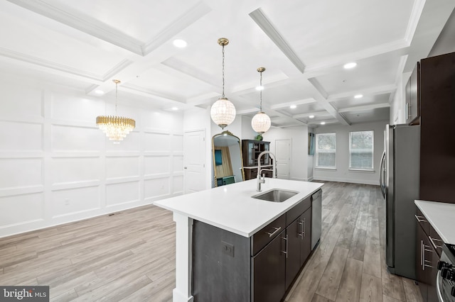 kitchen with a decorative wall, stainless steel appliances, coffered ceiling, a sink, and light wood-style floors