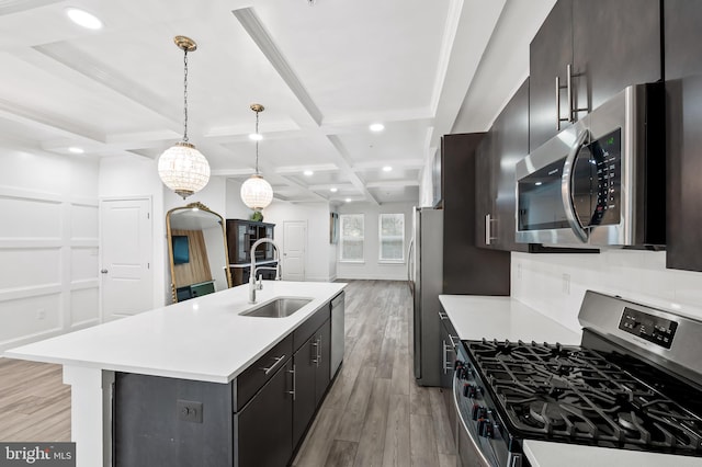 kitchen featuring light countertops, light wood-style flooring, appliances with stainless steel finishes, a sink, and coffered ceiling