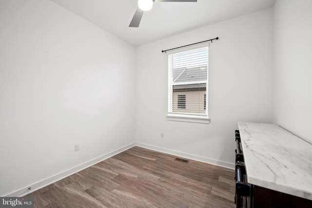 unfurnished room featuring a ceiling fan, wood finished floors, visible vents, and baseboards