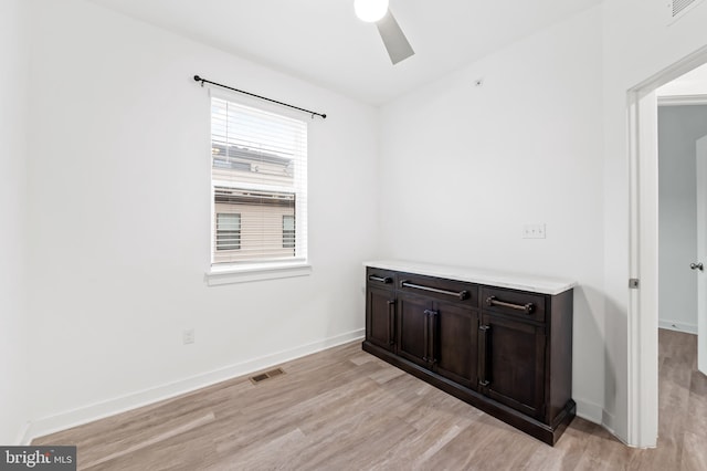 empty room with light wood-style floors, visible vents, ceiling fan, and baseboards