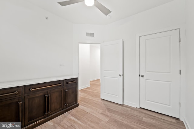 unfurnished bedroom featuring baseboards, a ceiling fan, visible vents, and light wood-style floors