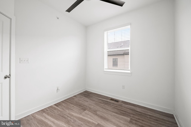 spare room featuring baseboards, visible vents, ceiling fan, and wood finished floors