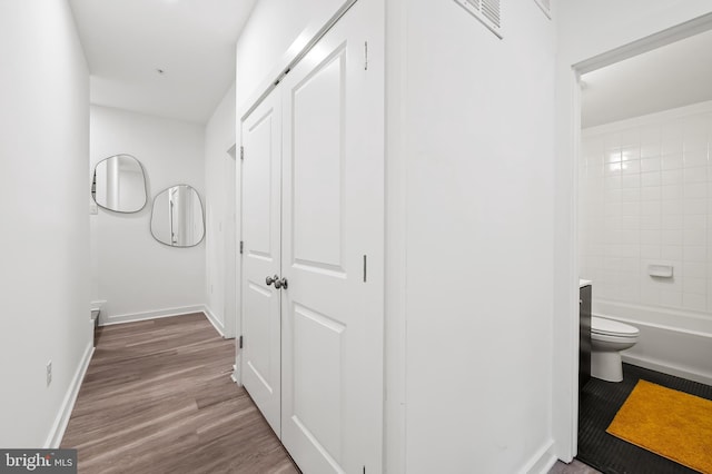 corridor with baseboards and wood finished floors