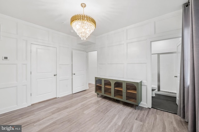 interior space with a notable chandelier, light wood-type flooring, and a decorative wall