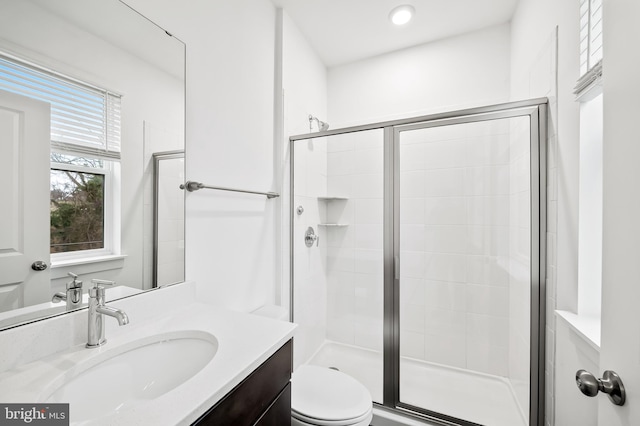 full bathroom featuring a stall shower, vanity, and toilet