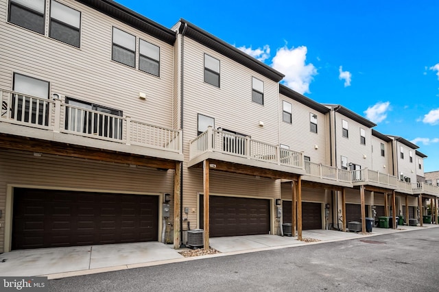 rear view of property featuring a garage, a residential view, and central air condition unit