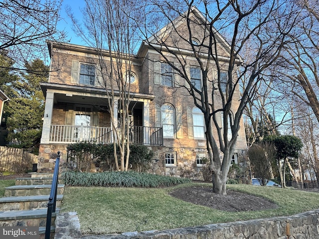 view of front facade featuring stone siding, brick siding, and a front lawn