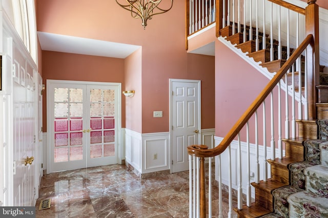 entrance foyer with french doors, a wainscoted wall, marble finish floor, visible vents, and a decorative wall