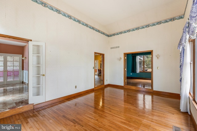 unfurnished room featuring light wood finished floors, visible vents, a wealth of natural light, and french doors