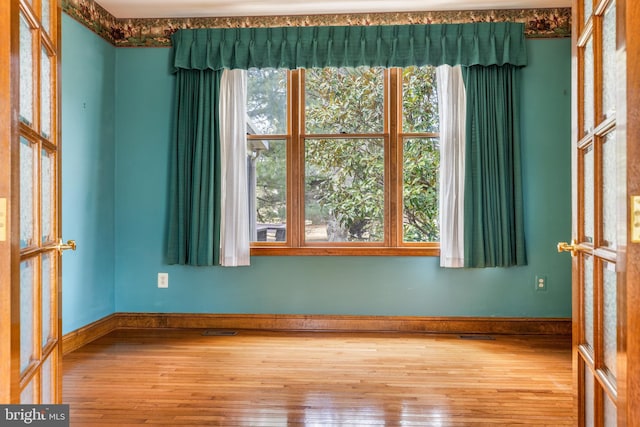 spare room with baseboards, visible vents, and hardwood / wood-style floors