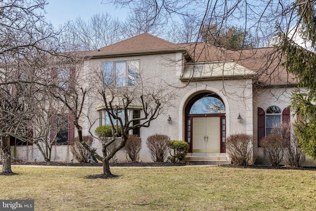 view of front of house featuring a shingled roof, entry steps, a front lawn, and stucco siding