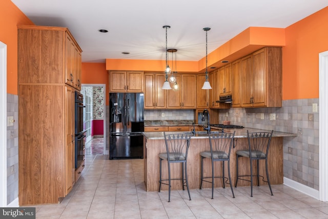 kitchen with tasteful backsplash, brown cabinets, decorative light fixtures, a peninsula, and black appliances