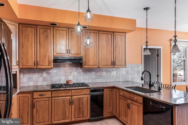 kitchen featuring under cabinet range hood, a peninsula, a sink, brown cabinets, and black appliances