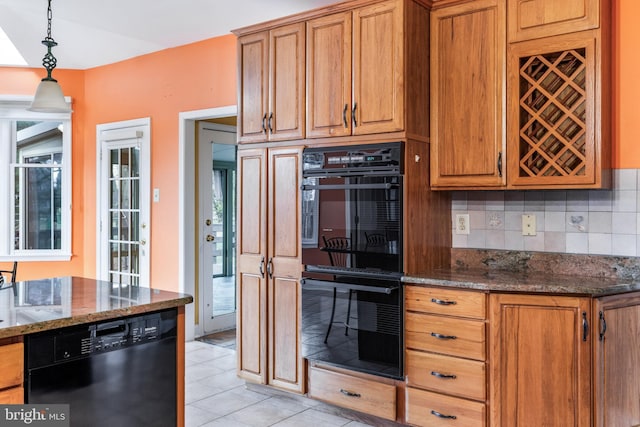 kitchen featuring dark stone counters, black appliances, tasteful backsplash, brown cabinetry, and decorative light fixtures