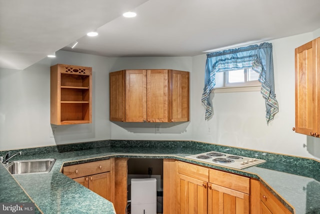 kitchen with brown cabinetry, dark countertops, white electric cooktop, a sink, and recessed lighting