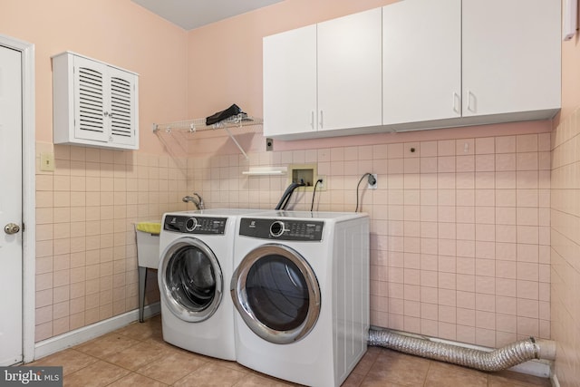 laundry room featuring cabinet space, washing machine and dryer, tile walls, and light tile patterned flooring