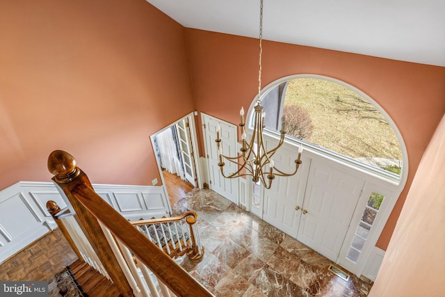 foyer entrance featuring a wainscoted wall, visible vents, and a decorative wall