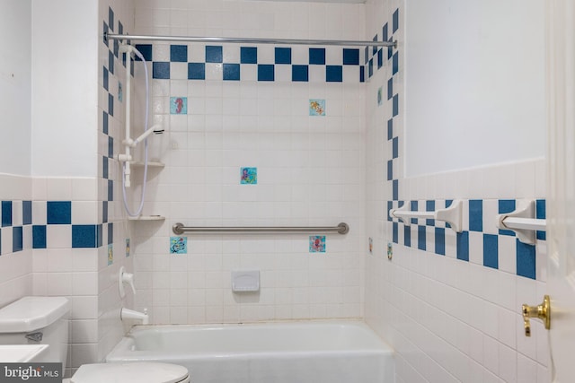 bathroom with wainscoting, bathtub / shower combination, toilet, and tile walls