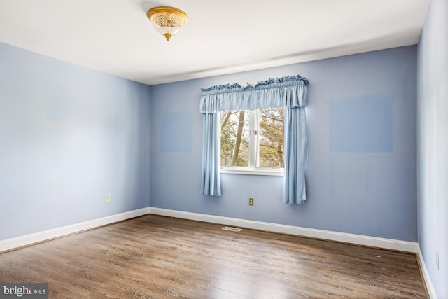 spare room featuring visible vents, baseboards, and wood finished floors