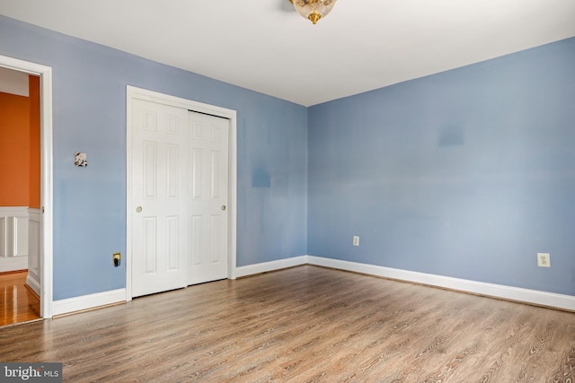 unfurnished bedroom featuring a closet, baseboards, and wood finished floors