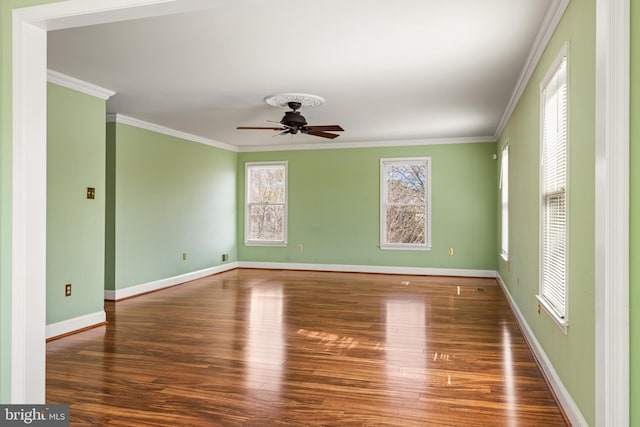 empty room with a ceiling fan, crown molding, baseboards, and wood finished floors