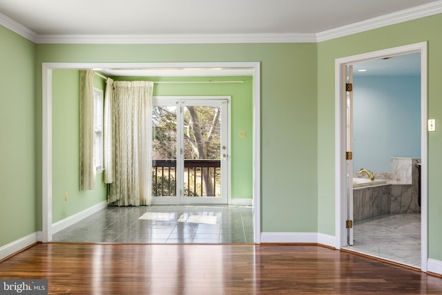 unfurnished room featuring baseboards, wood finished floors, and crown molding