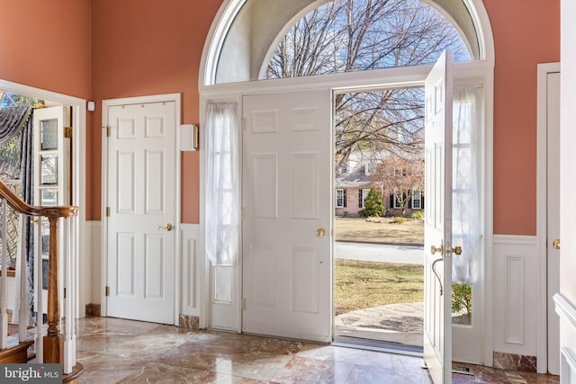 entryway with marble finish floor, a wainscoted wall, plenty of natural light, and stairs