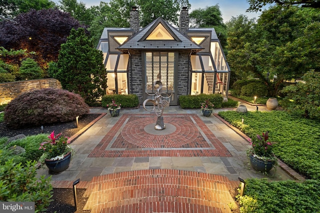 exterior space featuring stone siding, a chimney, and stucco siding